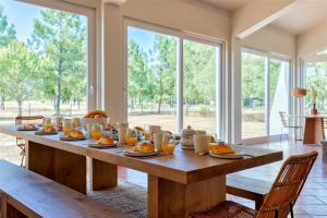 a wooden table with food on it in a room with windows at Monte dos Figos · Charming Villa with Private Pool close to Comporta in Grândola