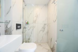 La salle de bains blanche est pourvue d'une douche et de toilettes. dans l'établissement Sol Apartments Corfu by Estia, à Corfou