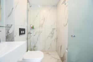 une salle de bain blanche avec toilettes et douche dans l'établissement Sol Apartments Corfu by Estia, à Corfou