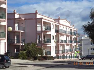 un bâtiment blanc avec balcon et voitures garées devant dans l'établissement St James Apartment, à Luz