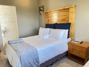 a bedroom with a large white bed with a wooden headboard at La Vue in Port Shepstone