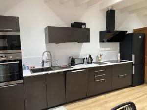 a kitchen with gray cabinets and a black refrigerator at CERES HOME in Montierchaume +10 photos
