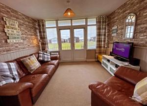 a living room with leather couches and a flat screen tv at Little Haven Chalet Withernsea in Withernsea