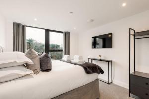 um quarto branco com uma cama grande e uma televisão em Aurora South em Poole