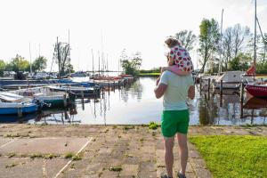 un hombre sosteniendo a un niño en su espalda en un puerto deportivo en De Koevoet, en Teroele