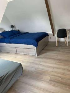 een slaapkamer met een bed met blauwe lakens en een houten vloer bij Village house 3 bedrooms large terrace - Dodo et Tartine in Villedieu-les-Poëles