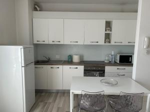 a kitchen with white cabinets and a white table and chairs at Casa Vanny in Colico +13 photos