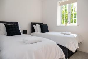 two white beds in a room with a window at Spacious Retreat with Parking: Ideal for Families & Contractors in York