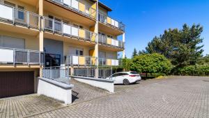 Un coche blanco aparcado delante de un edificio en Apartamenty PIAMOLA Powstańców Warszawy, en Stegna