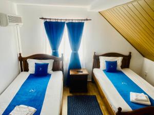 two beds in a room with blue curtains at HANUL PESCARILOR Mila 23 in Mila Douăzeci şi Trei