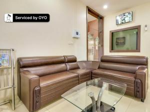 a living room with a leather couch and a glass table at Super Collection O Green Tree Near Beach Road in Alipur