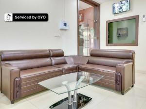 a living room with a brown leather couch and a glass table at Super Collection O Green Tree Near Beach Road in Alipur