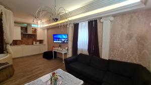 un soggiorno con divano nero e TV di Gostauto apartamentai a Vilnius