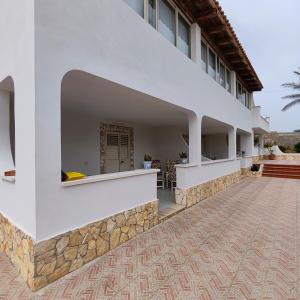 einen Außenblick auf ein weißes Gebäude mit einer Terrasse in der Unterkunft LA PERGOLA in Lampedusa