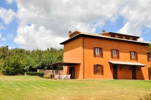 a large brick building with a table and chairs in a field at Villa i Noccioli - 18 posti letto, piscina, parco in Capranica