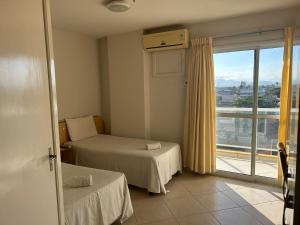 a bedroom with two beds and a large window at IDEAL HOTELS in Macaé
