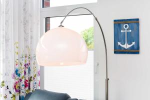 eine Stehlampe im Wohnzimmer mit blauem Sofa in der Unterkunft Passagendeck Nordseegartenpark in Bensersiel