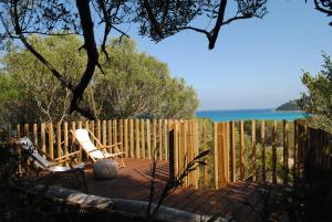 a wooden deck with two chairs and a fence at Cala Sinzias beach house with stunning views in Costa Rei
