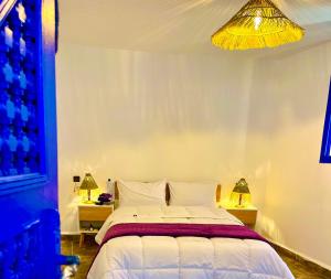 a bedroom with a bed and two night stands with lamps at Oceanside Surf & salsa in Aourir +4 photos