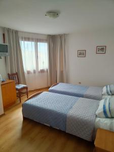a bedroom with two beds and a chair at Guest Rooms Melsambria in Nesebar