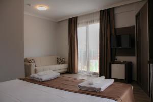 een slaapkamer met een bed, een bank en een raam bij Gulluk Life Hotel in Gulluk