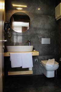 a bathroom with a sink and a toilet and a mirror at Gulluk Life Hotel in Gulluk