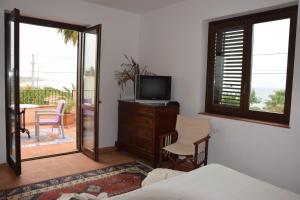 a bedroom with a bed and a television and a balcony at Villa Marinella in Marinella di Selinunte