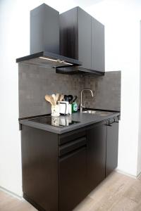 a kitchen with black cabinets and a sink at Magikrooms Kandy in Rome