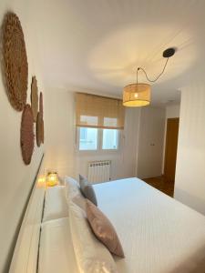 een slaapkamer met een wit bed met kussens bij Ollo de Llas in Foz