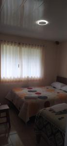 - une chambre avec 2 lits et une fenêtre avec des rideaux dans l'établissement Casa Vacacional Los Guayacanes, à Baños