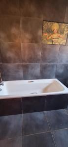 a bath tub in a bathroom with a picture on the wall at Henning nest guest house in Centurion +1 photo