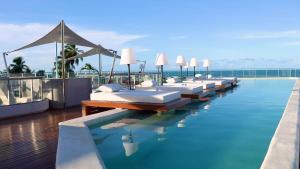 a row of beds on top of a swimming pool at Setai Yacht Premium - By Almare Flats in João Pessoa