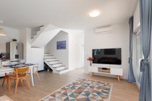 a white living room with a dining table and a tv at Papa's Court II Pasman Villa with pool in Pašman