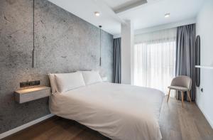 a bedroom with a white bed and a concrete wall at The Orange House Boutique Hotel and Upstairs Rooftop Bar Center of La Cala de Mijas 100m from the Beach in La Cala de Mijas