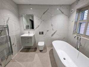 y baño con bañera, aseo y lavamanos. en Luxury 5* Didsbury Family Home en Mánchester