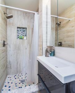 ein Badezimmer mit einem weißen Waschbecken und einer Dusche in der Unterkunft Boutique Vacation Rental Complex At Beach in Cocoa Beach