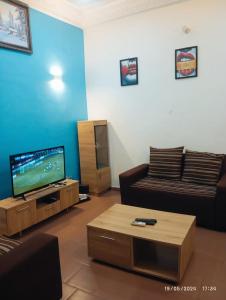 a living room with a couch and a flat screen tv at Richie club des rois in Agonkamè