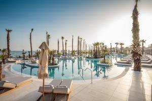 ヘルソニソスにあるEuropa Beach Hotel & Spaのヤシの木と椅子が並ぶスイミングプールと海