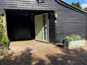 a black shed with a door and a patio at 2 Bed Barn - Sleeps 4 - Pets - Parking - Wifi in Downham Market