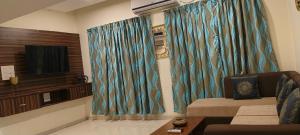 un soggiorno con tende blu e TV di Luxury 3BHK Villa With Swimming Pool in Candolim a Candolim