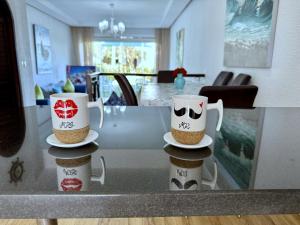 two coffee cups sitting on a glass table at Excelent Chalet Triplex in Kasr Rimal-Kabila Tetouan in M'diq