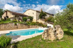 a swimming pool in front of a stone house at La Maison de Yûka in Plieux