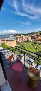 a red chair on a balcony with a view of a city at Moderno appartamento vista mare, con parcheggio privato in Portovenere
