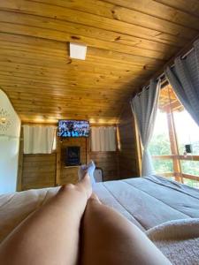 a person laying on a bed with their feet on it at chalecachoeiradochiador in Espera Feliz