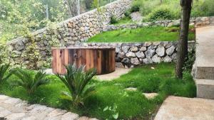 une boîte en bois assise dans l'herbe à côté d'un mur en pierre dans l'établissement RUSTICO, à Shirokë