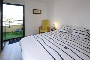 a bedroom with a bed and a chair and a window at Newquay Sunset in Dinard