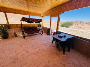 een afgeschermde veranda met een tafel en uitzicht op de woestijn bij Petra Royal Ranch in Wadi Musa