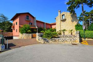 a house with a stone wall next to a street at Holiday Homes in Lignano 21665 in Lignano Sabbiadoro