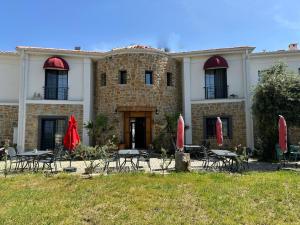 ein Gebäude mit Tischen und Stühlen davor in der Unterkunft Hotel Panaya in Gokceada Town