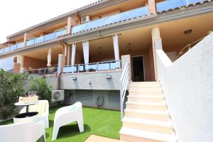 a balcony of a house with a lawn and stairs at Maravilloso adosado para 8 en entorno privilegiado by Hometels in Canet de Berenguer